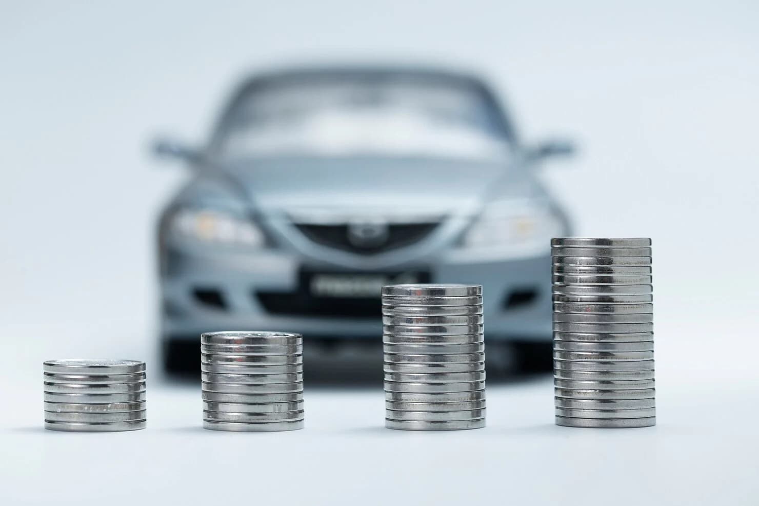Car with stacks of coins representing comparison of new car vs used car financing