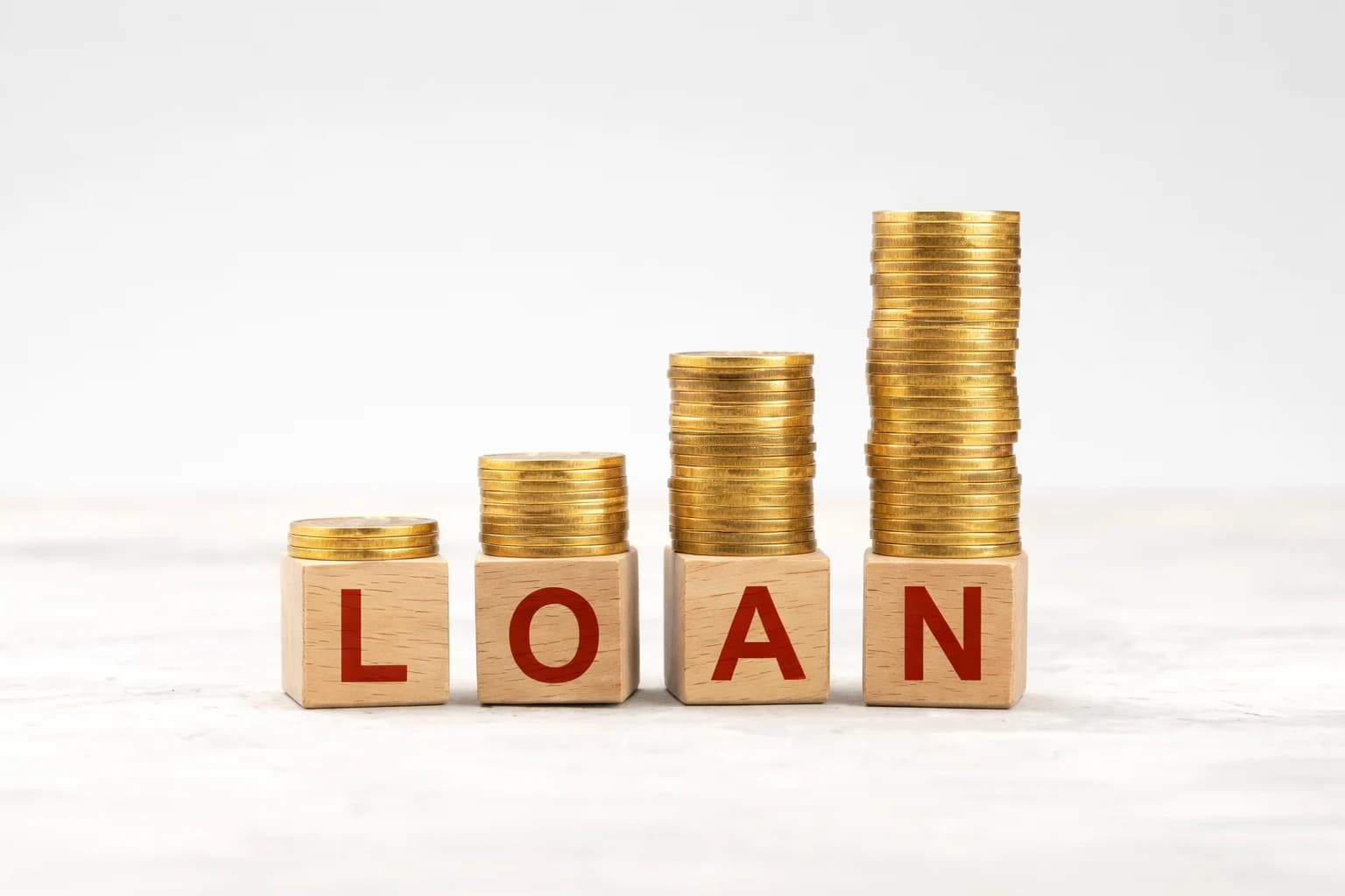 Wooden blocks spelling loan with stacked coins representing basic loan concepts and borrowing