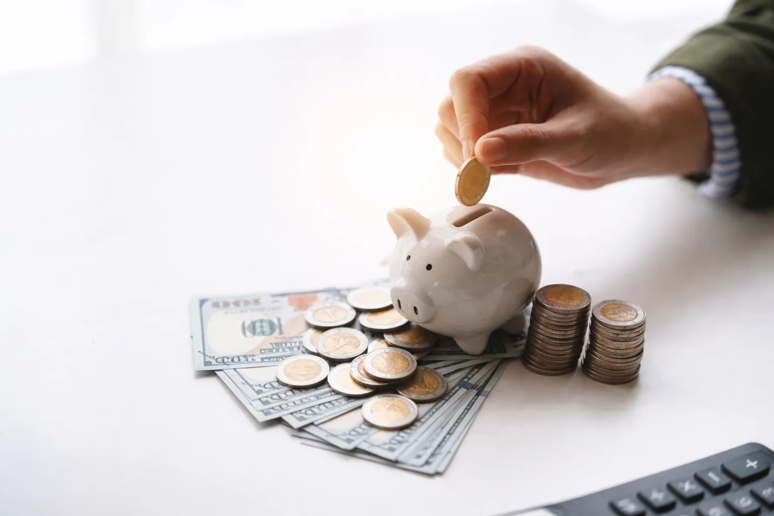 Hand placing coins into piggy bank representing savings planning and financial goals